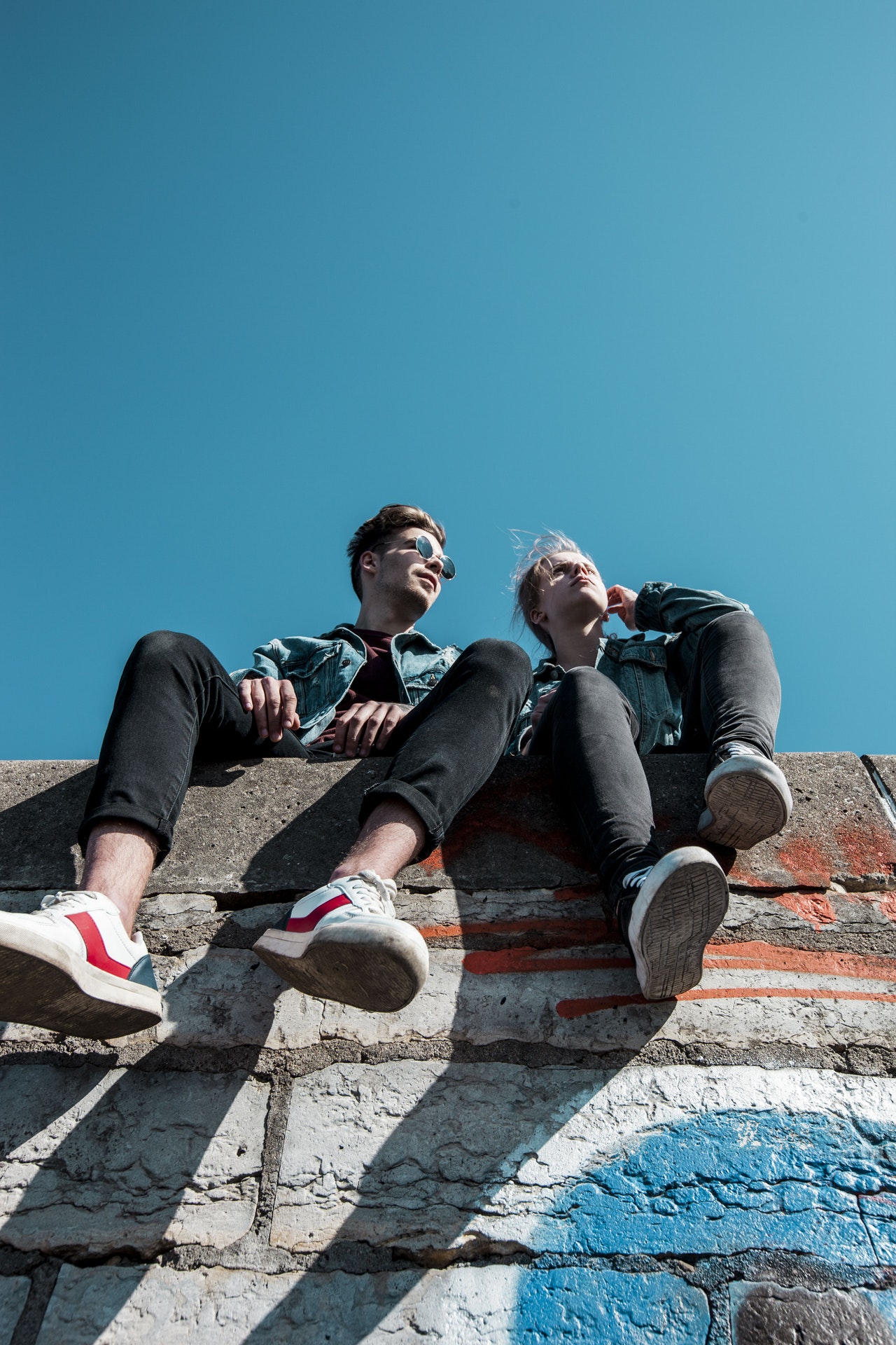 two college age men relaxing and sitting on top of the wall